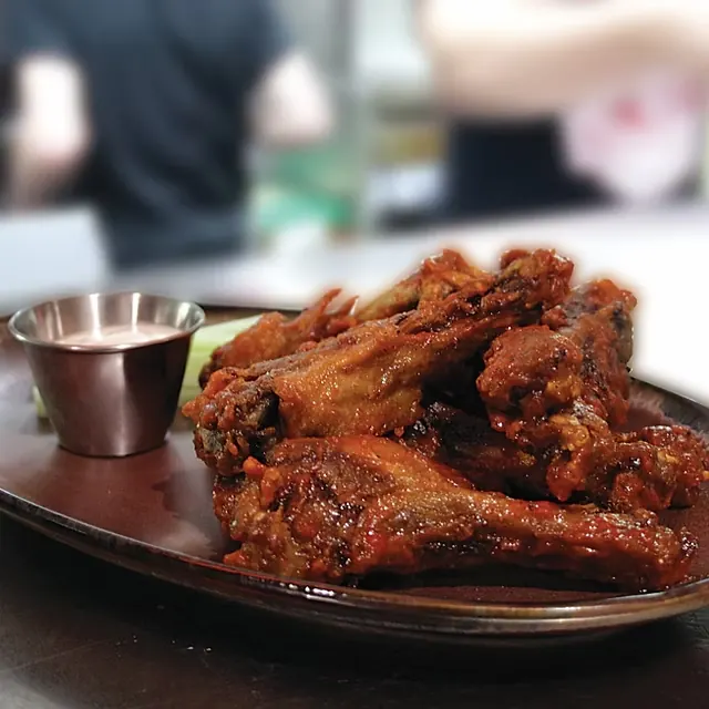 A plate of sauced chicken wings with dip